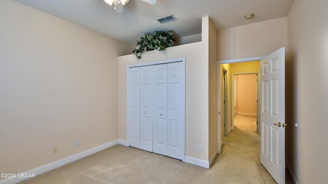 bedroom with a closet, a textured ceiling, light colored carpet, and ceiling fan