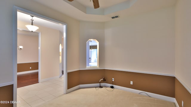 spare room with ceiling fan, light tile patterned floors, and a raised ceiling