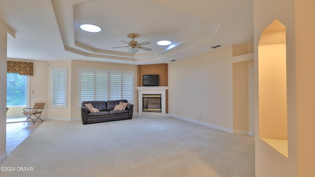 unfurnished living room featuring light carpet, ceiling fan, and a tray ceiling