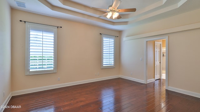 spare room featuring ceiling fan, dark hardwood / wood-style floors, and a tray ceiling