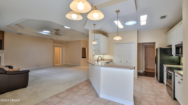 kitchen with appliances with stainless steel finishes, light carpet, hanging light fixtures, white cabinets, and kitchen peninsula