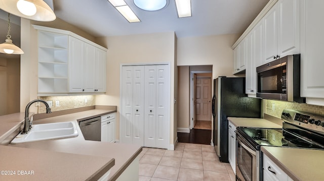 kitchen with light tile patterned flooring, stainless steel appliances, hanging light fixtures, sink, and white cabinets