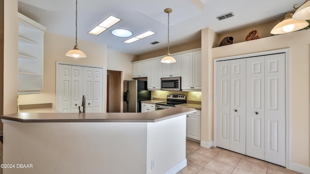 kitchen with light tile patterned flooring, appliances with stainless steel finishes, kitchen peninsula, white cabinets, and decorative backsplash