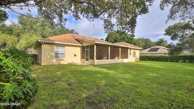 rear view of property featuring a sunroom and a yard