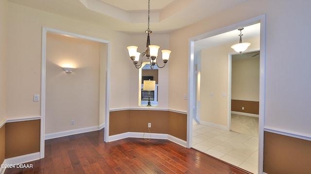 spare room with hardwood / wood-style flooring and a notable chandelier