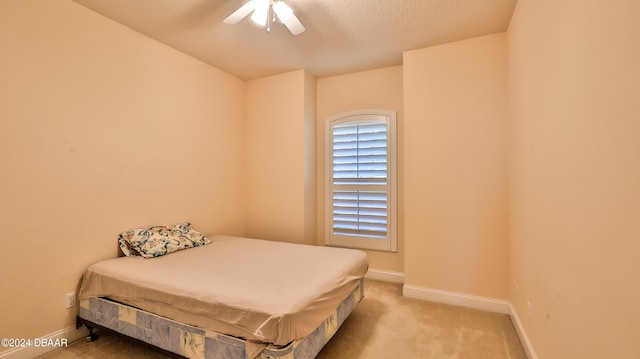 carpeted bedroom featuring ceiling fan and a textured ceiling