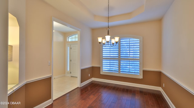 empty room featuring wood-type flooring, a healthy amount of sunlight, and a chandelier