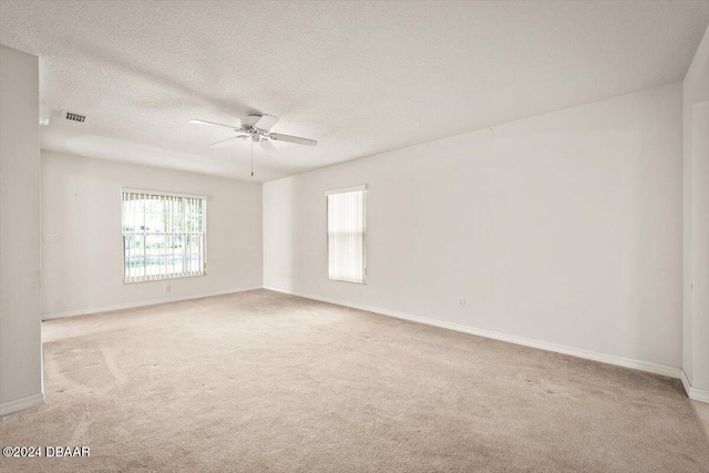 carpeted spare room with a textured ceiling and ceiling fan