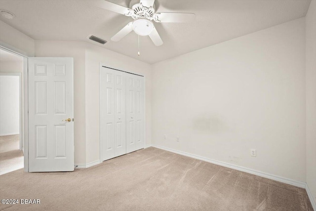 unfurnished bedroom featuring ceiling fan, a closet, and light colored carpet