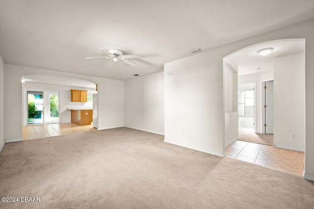 unfurnished living room featuring a textured ceiling, light colored carpet, and ceiling fan