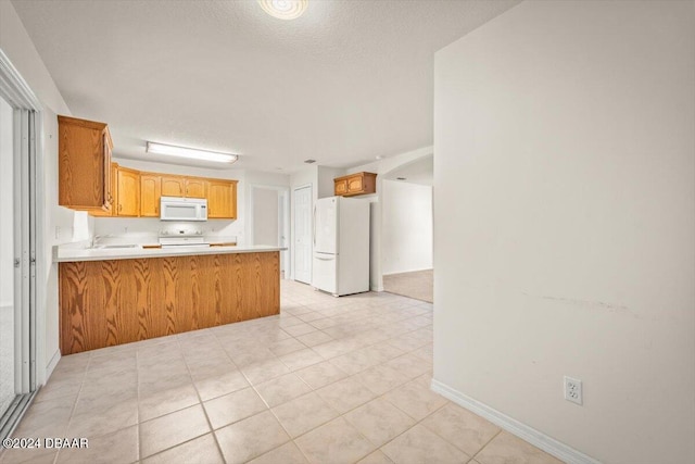 kitchen with kitchen peninsula, white appliances, a textured ceiling, and light tile patterned flooring