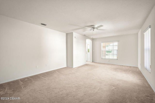 empty room featuring ceiling fan, a textured ceiling, and light carpet