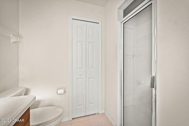 bathroom with a shower with shower door, vanity, toilet, and tile patterned floors