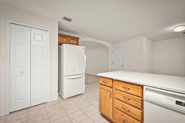 kitchen with a textured ceiling, light tile patterned flooring, and white appliances