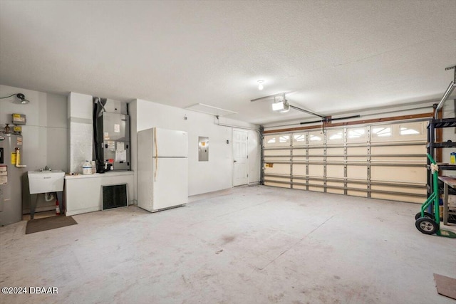 garage with sink, a garage door opener, heating unit, water heater, and white refrigerator