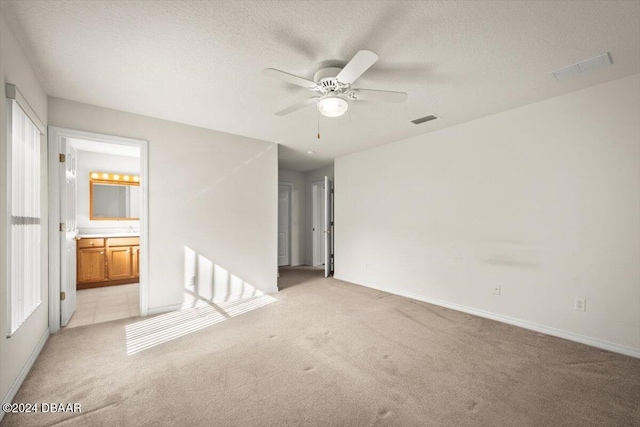 unfurnished room with a textured ceiling, light colored carpet, and ceiling fan