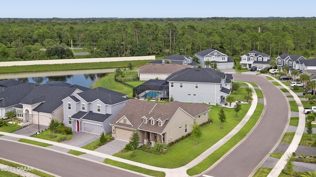 aerial view featuring a residential view, a wooded view, and a water view