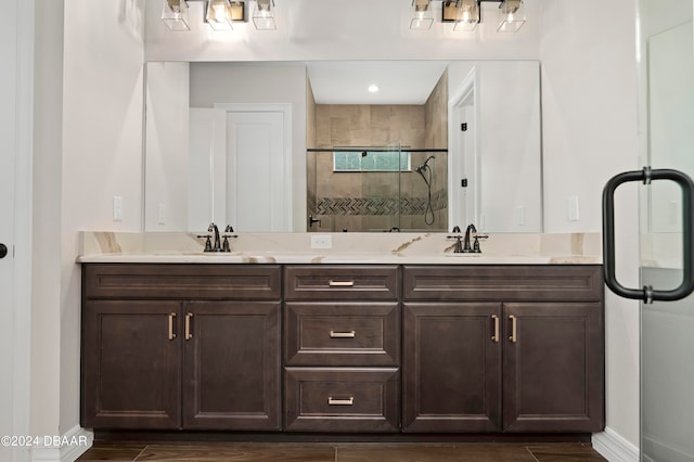 bathroom featuring double vanity, wood finished floors, a shower stall, and a sink