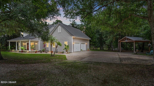 5711 John Anderson Hwy, Flagler Beach, FL 32136 - property exterior at dusk with a porch, a gazebo, driveway, a yard, and a garage