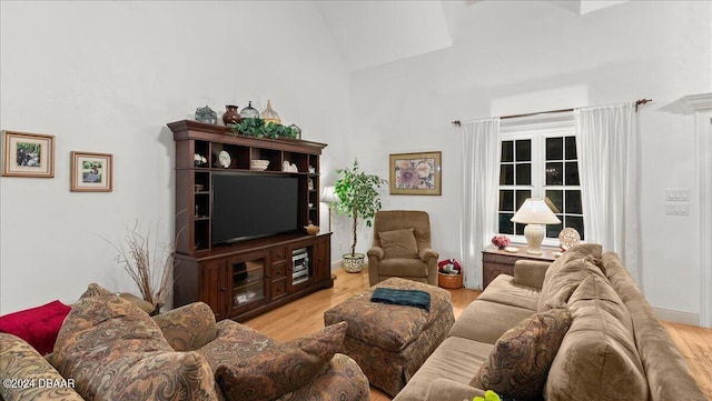 living room with light wood-type flooring and high vaulted ceiling