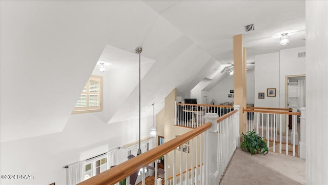 hallway featuring light colored carpet and lofted ceiling