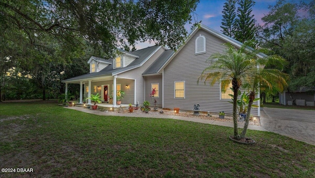 back house at dusk with a yard and a porch