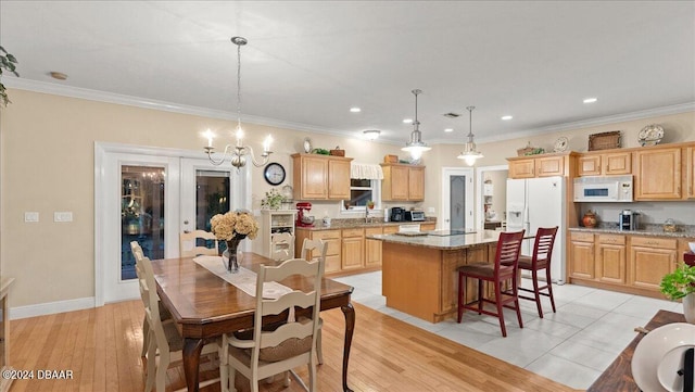 kitchen with light hardwood / wood-style floors, light stone countertops, white appliances, a kitchen island, and pendant lighting