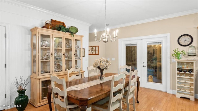 dining space featuring an inviting chandelier, french doors, crown molding, and light hardwood / wood-style flooring