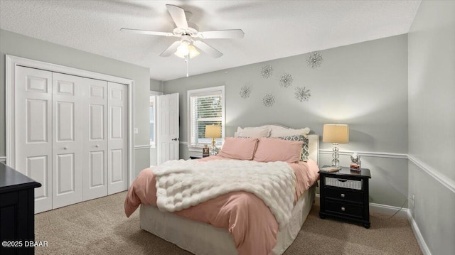 carpeted bedroom with ceiling fan, a closet, and a textured ceiling