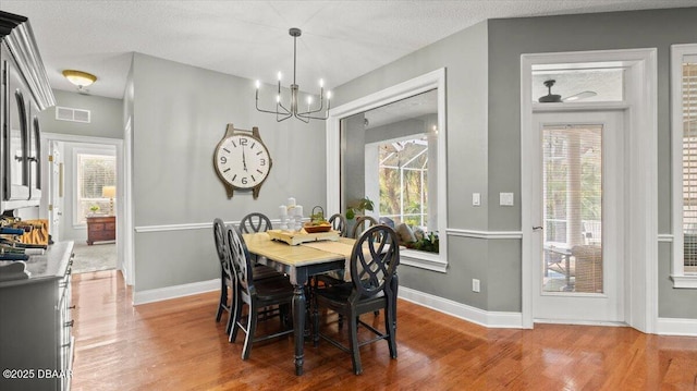 dining room featuring an inviting chandelier, wood-type flooring, and a textured ceiling