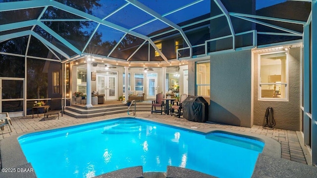 view of pool featuring french doors, a patio area, area for grilling, glass enclosure, and ceiling fan