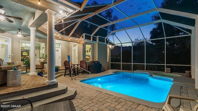 pool at dusk featuring a lanai, ceiling fan, a patio area, grilling area, and an in ground hot tub