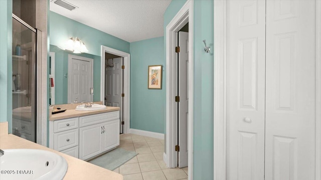 bathroom with vanity, a shower with door, tile patterned flooring, and a textured ceiling