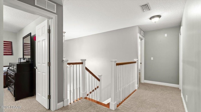 corridor featuring light colored carpet and a textured ceiling