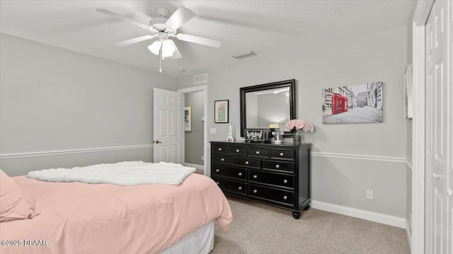 carpeted bedroom featuring ceiling fan and a textured ceiling