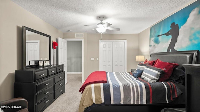 bedroom featuring ceiling fan, a closet, light carpet, and a textured ceiling