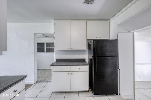 607 Marlene Dr, Holly Hill, FL 32117 - kitchen with freestanding refrigerator, dark countertops, white cabinets, and light tile patterned floors