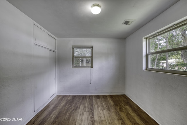 607 Marlene Dr, Holly Hill, FL 32117 - unfurnished bedroom with multiple windows, dark wood-type flooring, and a closet