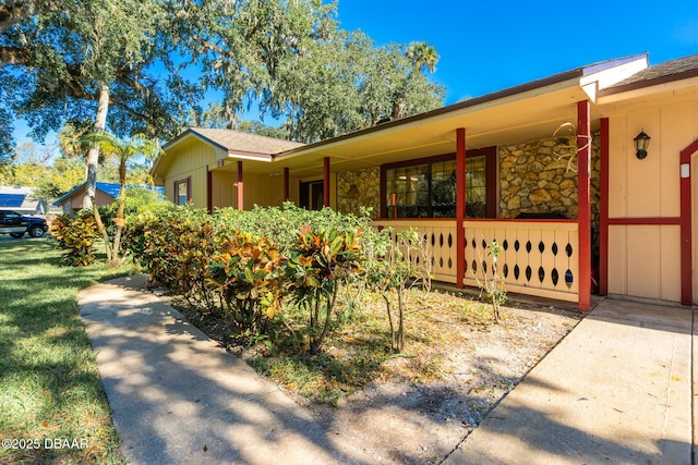 894 Quarters Ct, Port Orange, FL 32129 - view of side of property with covered porch, stone siding, and a shingled roof