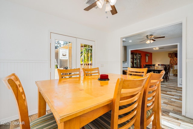894 Quarters Ct, Port Orange, FL 32129 - dining space featuring a ceiling fan, light wood-style floors, and a wainscoted wall