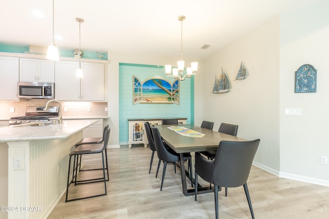 dining space with light hardwood / wood-style floors, a chandelier, and sink