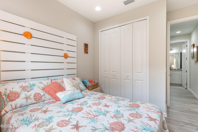 bedroom with light hardwood / wood-style floors and a closet