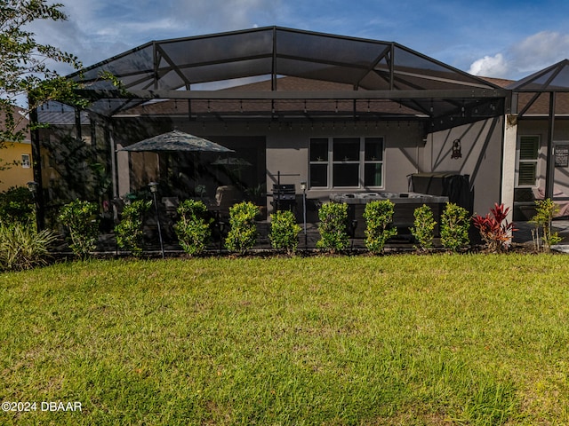 exterior space with a patio, a yard, glass enclosure, and a jacuzzi