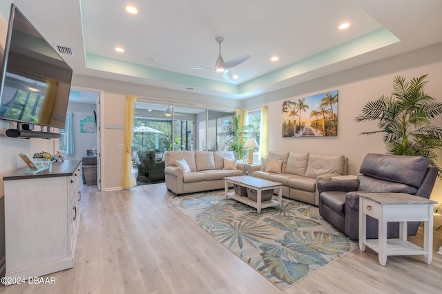 living room with ceiling fan, light hardwood / wood-style flooring, and a tray ceiling