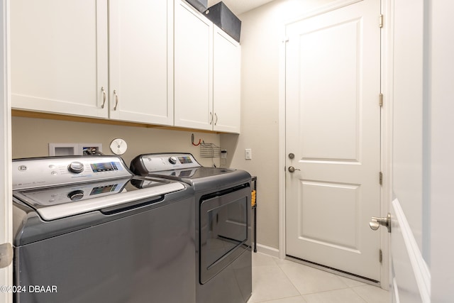 laundry area featuring washing machine and dryer, cabinets, and light tile patterned flooring