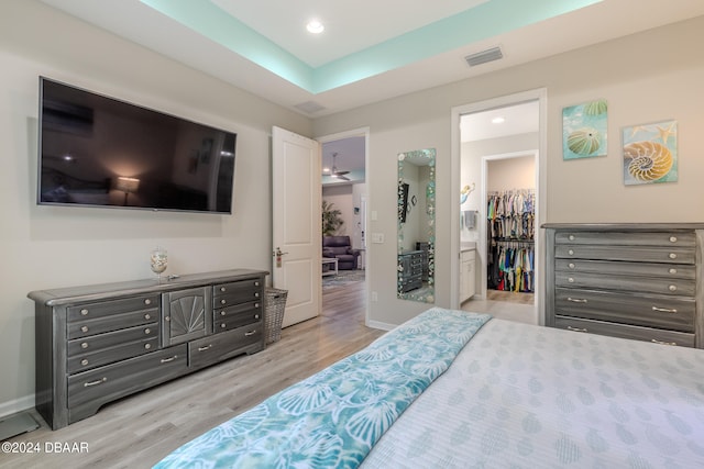 bedroom with ensuite bathroom, a closet, light wood-type flooring, and a spacious closet