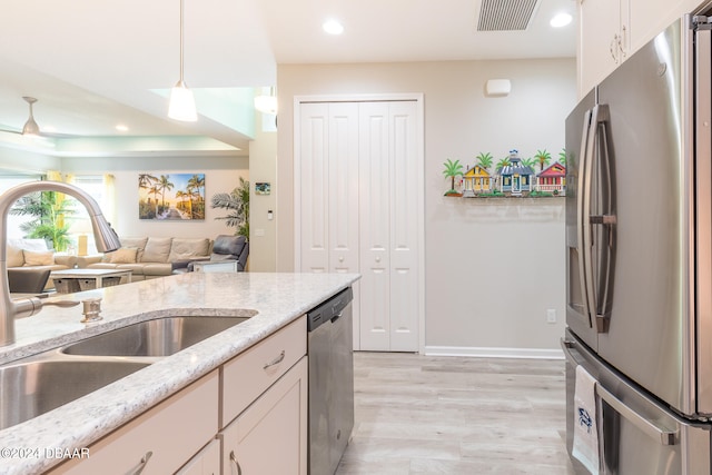 kitchen with stainless steel appliances, sink, pendant lighting, light wood-type flooring, and white cabinetry