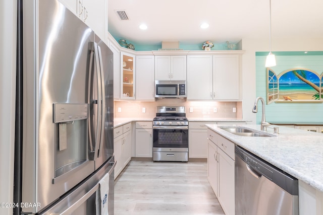 kitchen with white cabinets, stainless steel appliances, sink, and light hardwood / wood-style flooring