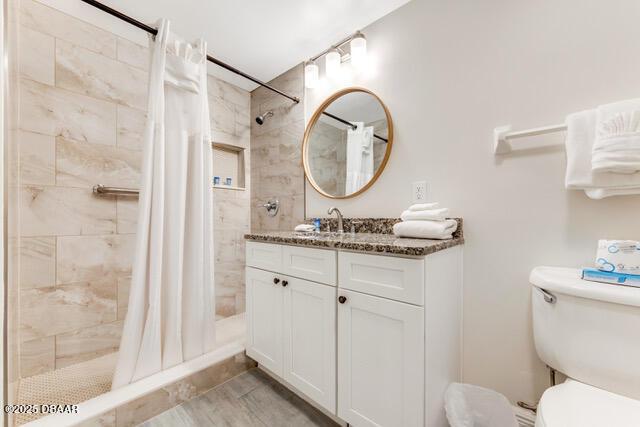 full bathroom with toilet, a shower stall, and vanity