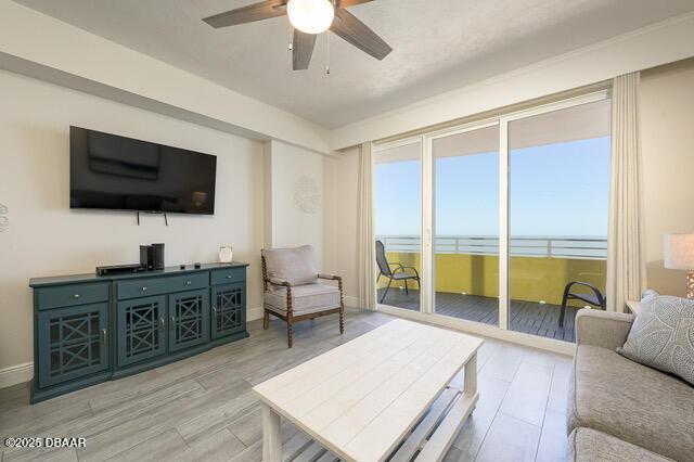 living area featuring light wood finished floors, ceiling fan, and baseboards